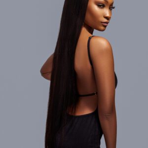 A woman with long hair standing in front of a gray background.