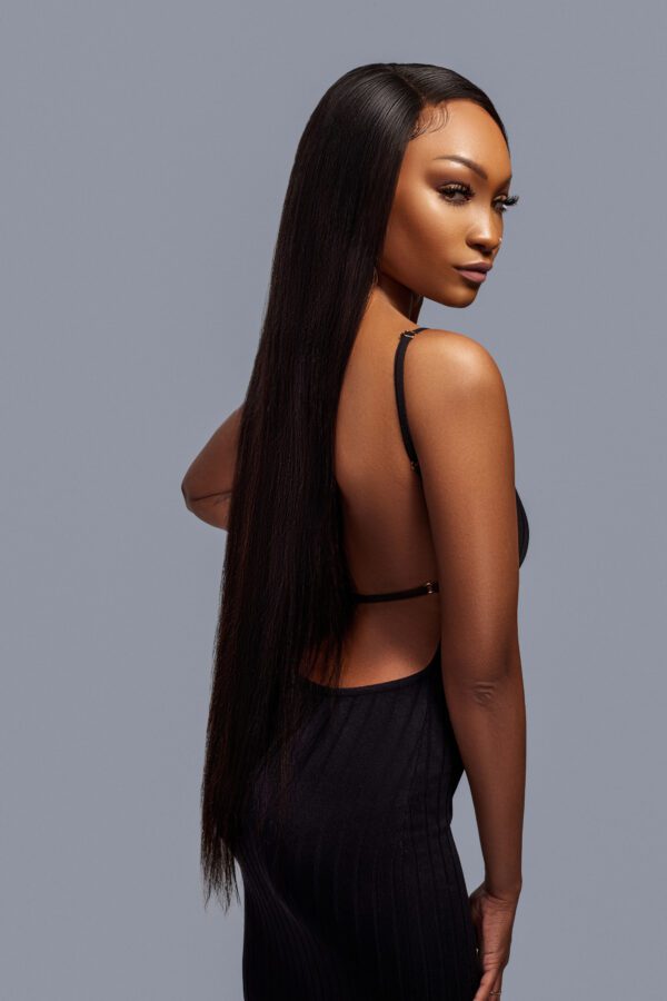 A woman with long hair standing in front of a gray background.